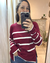 Mujer posando frente a un espejo el Sweater Fidel en color bordó con rayas blancas, cuello redondo y tajos laterales – Tiendas Eclipse