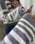 Mujer posando frente a espejo un Sweater Iguazú color gris con crudo. Enfocando en detalle la manga y el tejido.