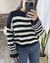 Mujer posando frente a espejo un Sweater Iguazú color negro con crudo.