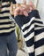 Mujer posando frente a espejo un Sweater Iguazú color negro con crudo. Enfocando en detalle la manga y el tejido.