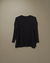 Sweater negro de mujer, modelo Over, de manga larga con puños acanalados sobre fondo neutro