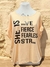 Remera de mujer color durazno con estampado de frases motivacionales en negro y detalles brillantes.