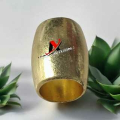 Entremeio espaçador dourado com acabamento fundido, medindo 17x14mm, apresentado entre plantas decorativas.