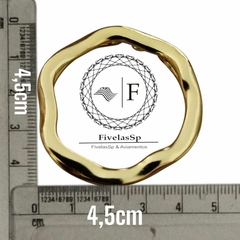 Fivela metal dourada em formato de medalha, medindo 4,5 cm, com régua ao fundo para referência de tamanho.