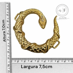 Fivela metálica em formato de serpente com detalhes em strass, medindo 7,5 cm de largura e 7,0 cm de altura.