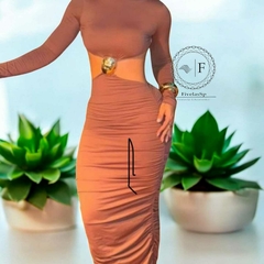 Mulher vestindo vestido justo cor terracota com fivela dourada modelo tartaruga na cintura, ao fundo plantas suculentas em vasos brancos