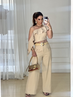 Mulher posando em um espelho usando um conjunto cropped e calça alfaiataria na cor bege, com detalhes elegantes.