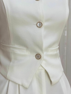 Detalhe da blusa do conjunto Taís, com botões dourados e tecido branco.