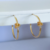 Brinco argola dourado com detalhes em nó cravejado em zircônia.