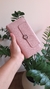 Carteira de mão grande rosa com textura em couro sintético, detalhe de botão decorativo e zíper, sendo segurada por uma mão feminina