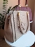 Imagem de uma bolsa feminina grande de ombro com alça trançada, na cor bordô, com um chaveiro em forma de urso; ao fundo, uma bolsa na cor nude.