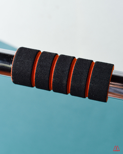Detalle de la barra puerta extensible cromada con empuñaduras de goma negra y naranja, ideal para ejercicios de fitness.