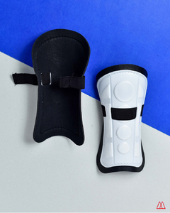 Canilleras para adultos de fútbol y hockey, mostrando un diseño negro y blanco, con correas ajustables.