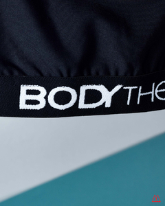 Detalle del top deportivo de Lycra de la marca Bodytherm, mostrando el logotipo en la banda inferior.