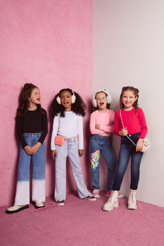 Quatro crianças sorrindo, vestindo blusas térmicas de manga longa e calças jeans, em um cenário com fundo rosa.