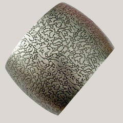 Brazalete de diseño con acabado simil plata antigua, texturizado con patrones ornamentales.