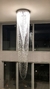 Lustre para pé direito duplo com design de véu de noiva, apresentando correntes de cristal que refletem a luz, instalado em um ambiente moderno.