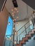 Imagem de lustres pendentes com lâmpadas expostas em um ambiente moderno, destacando a iluminação e a escadaria ao fundo.