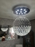 Lustre de cristal com formato esférico, pendurado no teto, iluminando o ambiente com seus detalhes brilhantes.