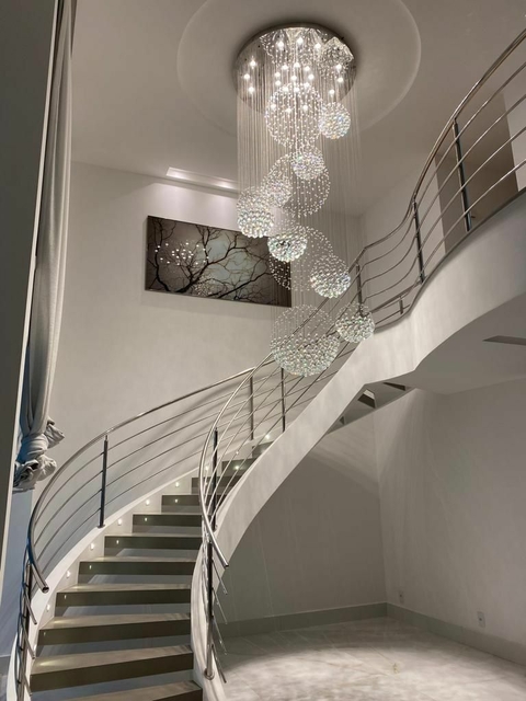 Escada elegante com lustre de cristal suspenso, criando um ambiente sofisticado e iluminado.