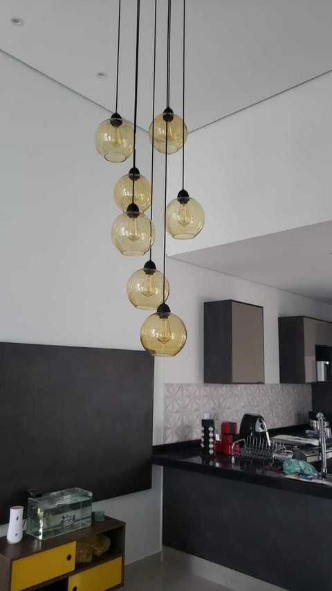 Lustre pendente com seis globos âmbar em uma cozinha moderna.