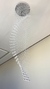 Um lustre de cristal com design moderno, apresentando uma cascata de contas transparentes penduradas, instalado em um teto claro.