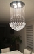 Iluminação de lustre em cristal com design moderno, pendurado ao teto, iluminando um ambiente interno.