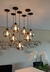 Iluminação pendente da Linha Sarvah Fumê Espelhado com lâmpadas em formato esférico, em ambiente moderno com orquídeas brancas ao fundo.