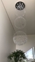 Um lustre de cristal com três grandes esferas penduradas, refletindo luz em um ambiente moderno e elegante.