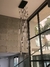 Lustre moderno da linha Dunáh com vidro transparente, pendurado em um ambiente com paredes de concreto e janelas grandes.