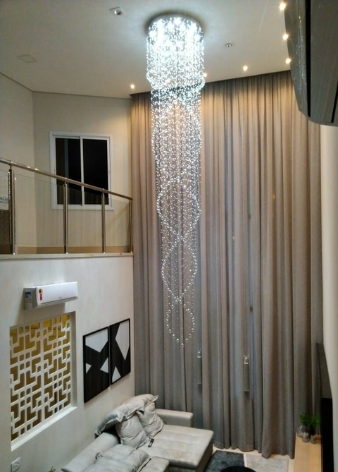 Lustres da Linha Cristal Zafira pendurados em um ambiente com cortinas e sofá.