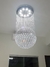 Lustre de cristal em formato esférico com luzes LED, pendurado no teto.