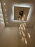 Imagem de um lustre moderno da Linha Dunáh, com lâmpadas em vidro transparente penduradas em um teto iluminado.