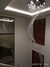 Um lustre da Linha Cristal Gênesis pendurado em um teto, com cristais formando um padrão fluido e iluminação suave.
