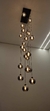 Um lustre moderno com várias esferas de vidro fumê espelhado, pendurado no teto, iluminando o ambiente com luzes quentes.