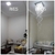 Antes e depois de uma sala de estar, mostrando a transformação com a instalação de um lustre da Linha Cristal DNA.