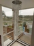 Lustre de cristal em formato espiral suspenso em ambiente com janelas amplas, oferecendo vista externa.