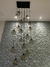 Decoração com lustres de vidro fumê pendurados em um teto, com parede de azulejos texturizados ao fundo.