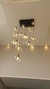 Lustre moderno com várias lâmpadas em vidro transparente, pendurado em um teto branco.