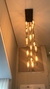 Um lustre moderno da Linha Dunáh em vidro fumê, pendurado no teto, com várias lâmpadas iluminadas, criando um ambiente aconchegante.