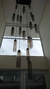 Um lustre moderno da Linha Dunáh, com tubos de vidro fumê pendurados, iluminando um ambiente contemporâneo.