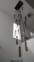Um lustre moderno da linha Dunáh com vidro fumê, pendurado em um ambiente contemporâneo, exibindo várias lâmpadas em diferentes alturas.