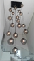 Um lustre moderno com várias lâmpadas em globos de vidro fumê, pendurado em um teto alto.