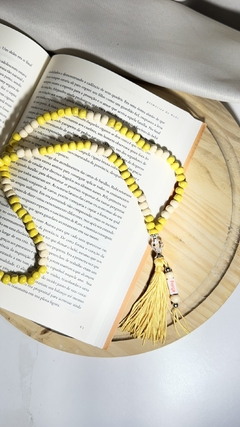 Japamala amarelo em cima de um livro aberto, com detalhes em amarelo e uma franja amarela.