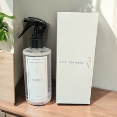 Frasco de Água Perfumada Floral da marca Fiori For Home, com embalagem ao lado, em um ambiente iluminado.