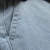 Detalhe do tecido da calça cargo plus size jeans delave, mostrando a textura e costura em azul claro.