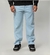Calça cargo jeans delave azul clara usada por modelo, com bolso lateral e tênis preto