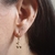 Brinco de argolinha fechada com pingente de duas cerejinhas folheado a ouro 18k