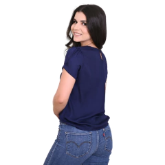Modelo feminina sorrindo, usando uma blusa azul escura e jeans, vista de costas.