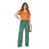 Mulher posando com blusa laranja e calça verde, segurando uma bolsa.